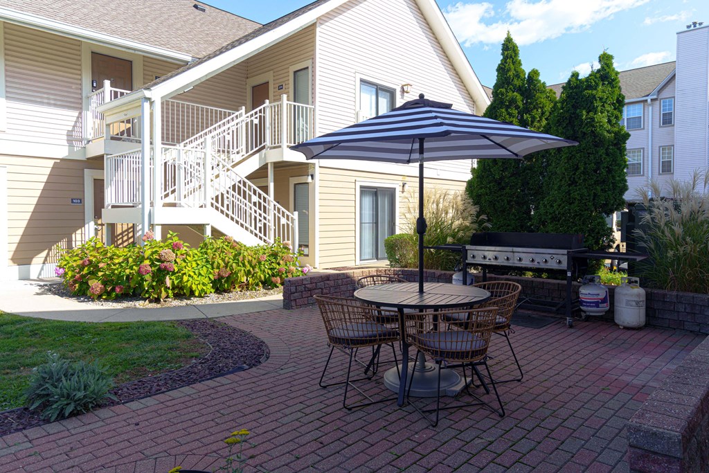 a patio with a table and chairs in front of a house